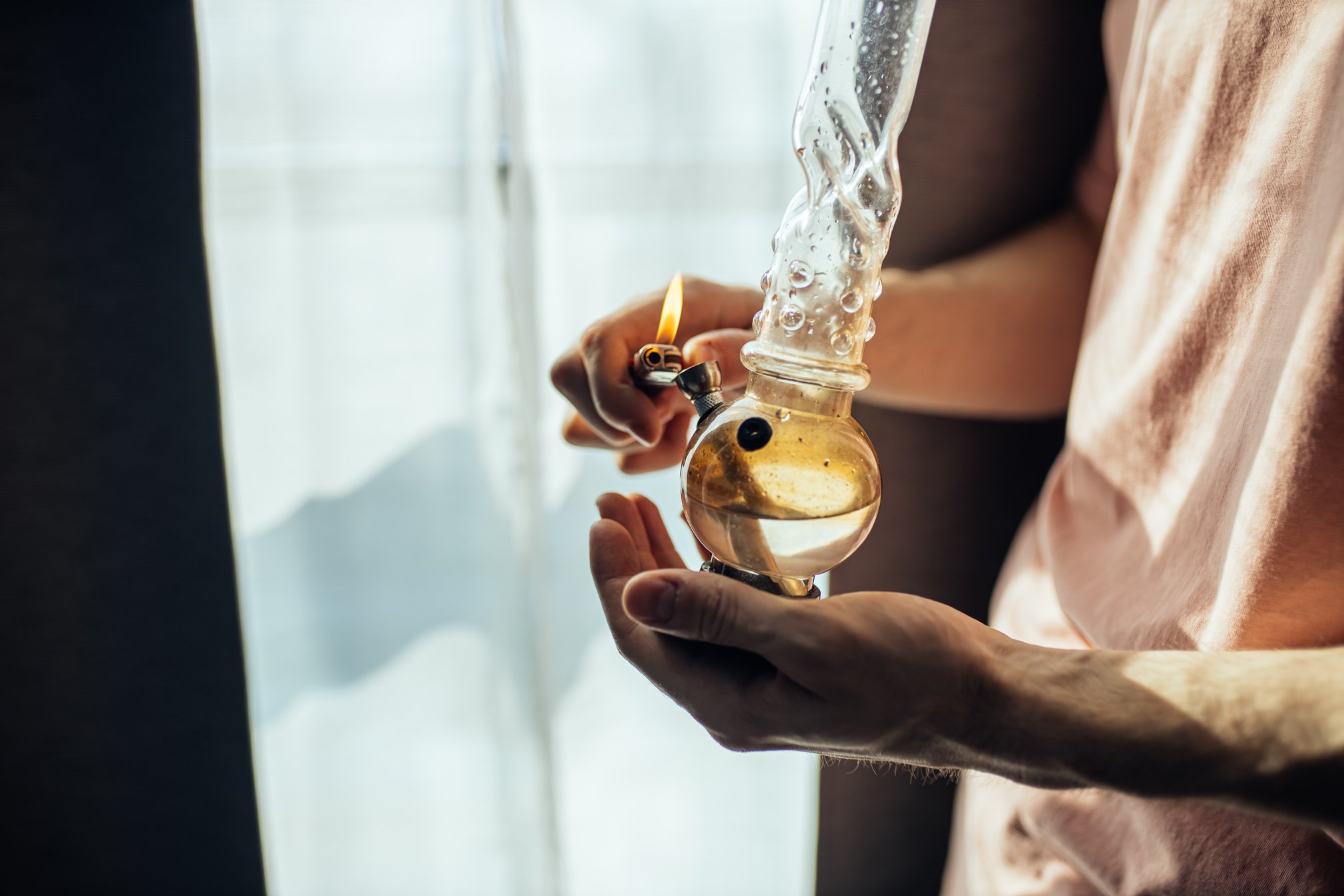 cropped man use bong with cannabis